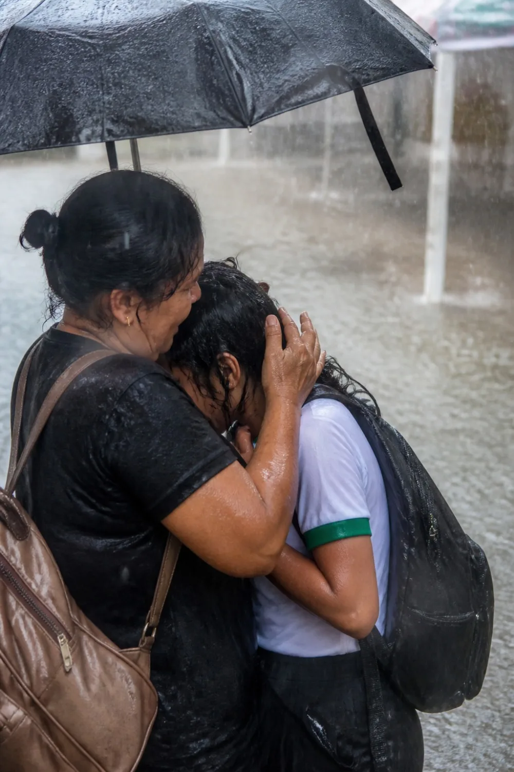 primer plano de una calle urbana inundada por lluvias torrenciales, reflejando luces de vehículos lejanos.