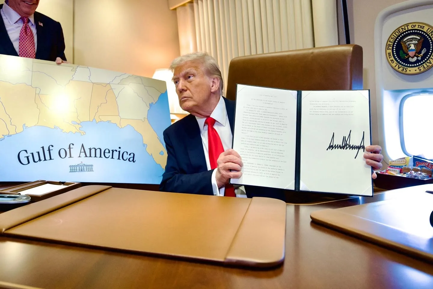 Donald Trump en su despacho sosteniendo un decreto recién firmado