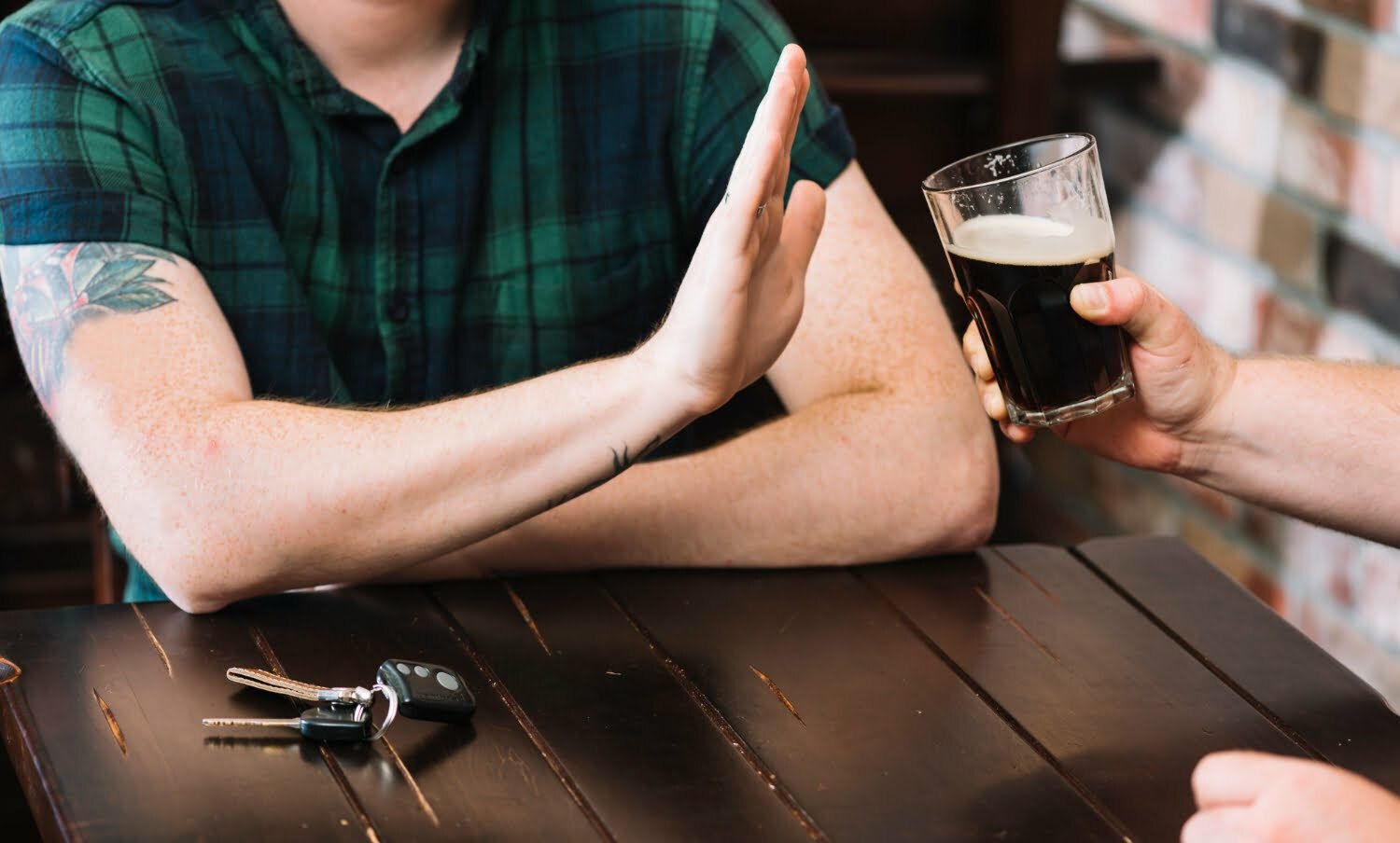 hombre en una mesa rechazando una bebida / dejas de tomar alcohol