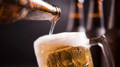 sirven cerveza en un vaso de vidrio con botellas de licor al fondo | Consumo moderado de cerveza alcohol - Esta marca de cerveza anunció que no subirá sus precios en Colombia este fin de año