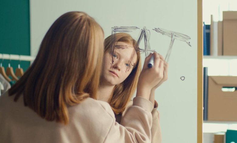 adolescente con cara de tristeza escribiendo en un espejo la palabra gorda en inglés - la relación entre la nutrición y la salud mental