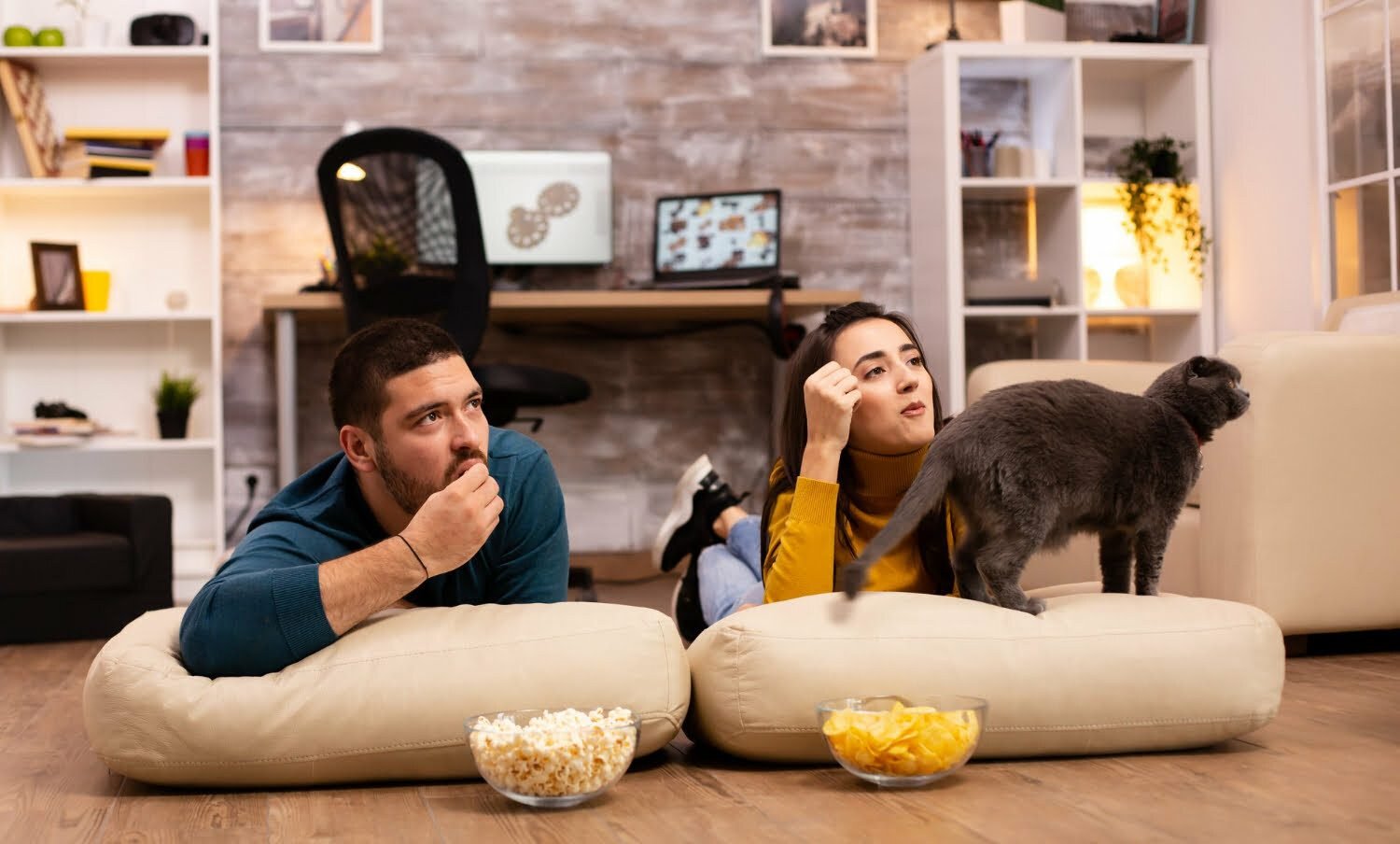 pareja en una relación, sentados en el suelo y viendo la televisión en su sala de estar