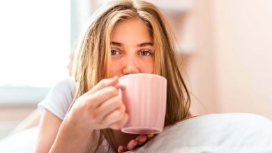 Mujer tomando café antes del desayuno, mientras está acostada en la cama - café en ayunas