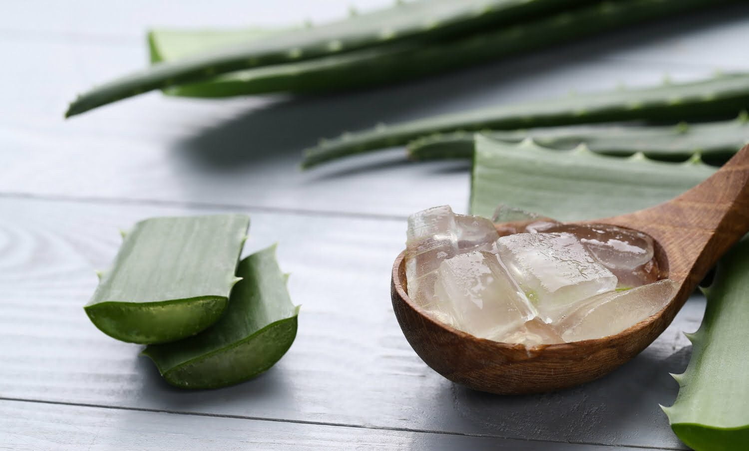 trozos de aloe vera para eliminar el acne, sobre cuchara de madera hojas de la planta.