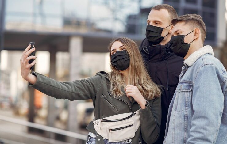 tres personas con tapabocas haciéndose un selfie en la calle