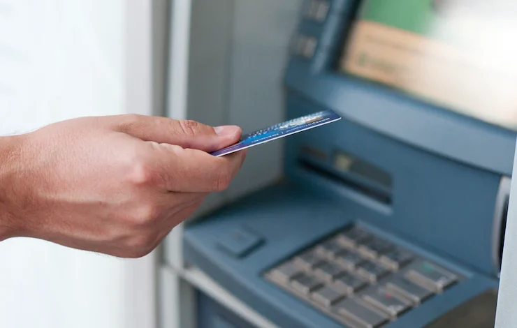 mano que inserta la tarjeta del cajero automático en la máquina de banco para retirar - Los bancos que más cobran por el uso de tarjeta débito y retiro en cajeros en fin de año