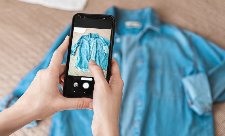 Mujer tomando foto de una camiseta de denim en un smartphone / vender en Internet