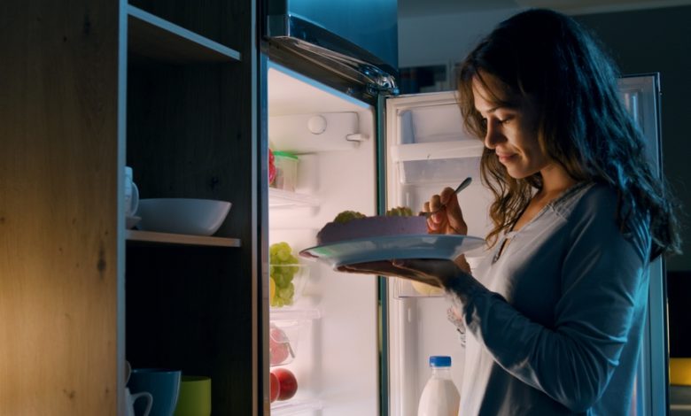 mujer hambrienta comiendo un aperitivo de medianoche / antojos de dulce