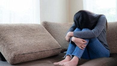 joven con depresión sentada en un mueble, con su cabeza entre las piernas / vacío emocional / autoabandono / bienestar / la pianista / depresión posparto