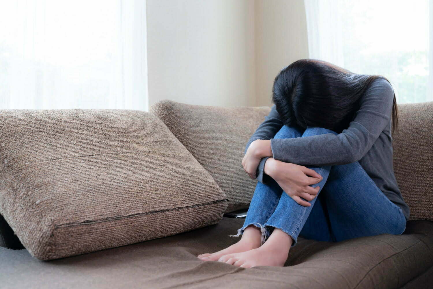 joven con depresión sentada en un mueble, con su cabeza entre las piernas / vacío emocional / autoabandono / bienestar / la pianista / depresión posparto