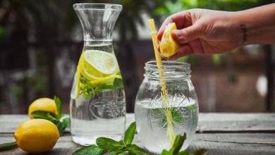 mano exprimiendo limón en un vaso de agua / limón en ayunas /agua de apio con limón