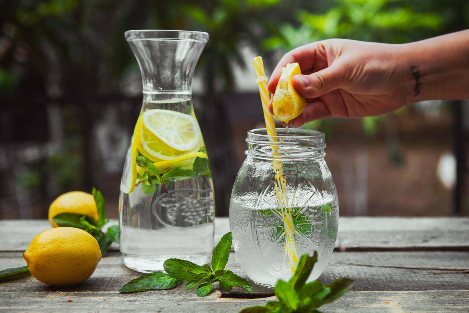 mano exprimiendo limón en un vaso de agua / limón en ayunas /agua de apio con limón