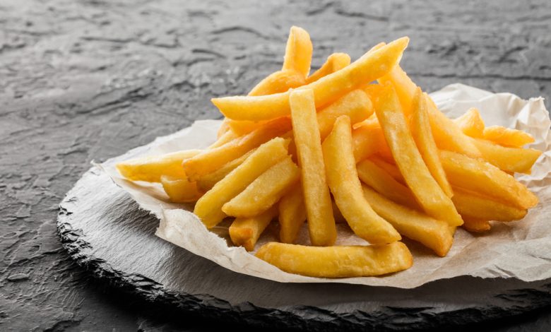 Sabrosas papas fritas en papel sobre fondo de piedra negra / papas a la francesa / vista