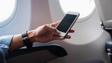 Mujer con la mano usando un smartphone en avión / modo avión