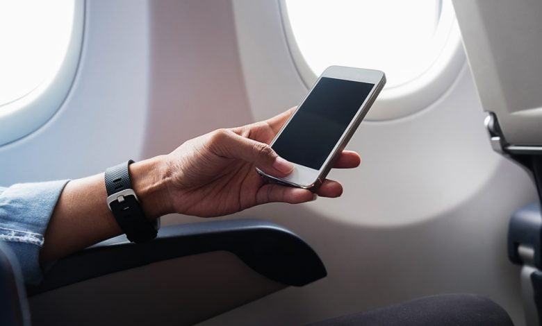 Mujer con la mano usando un smartphone en avión / modo avión