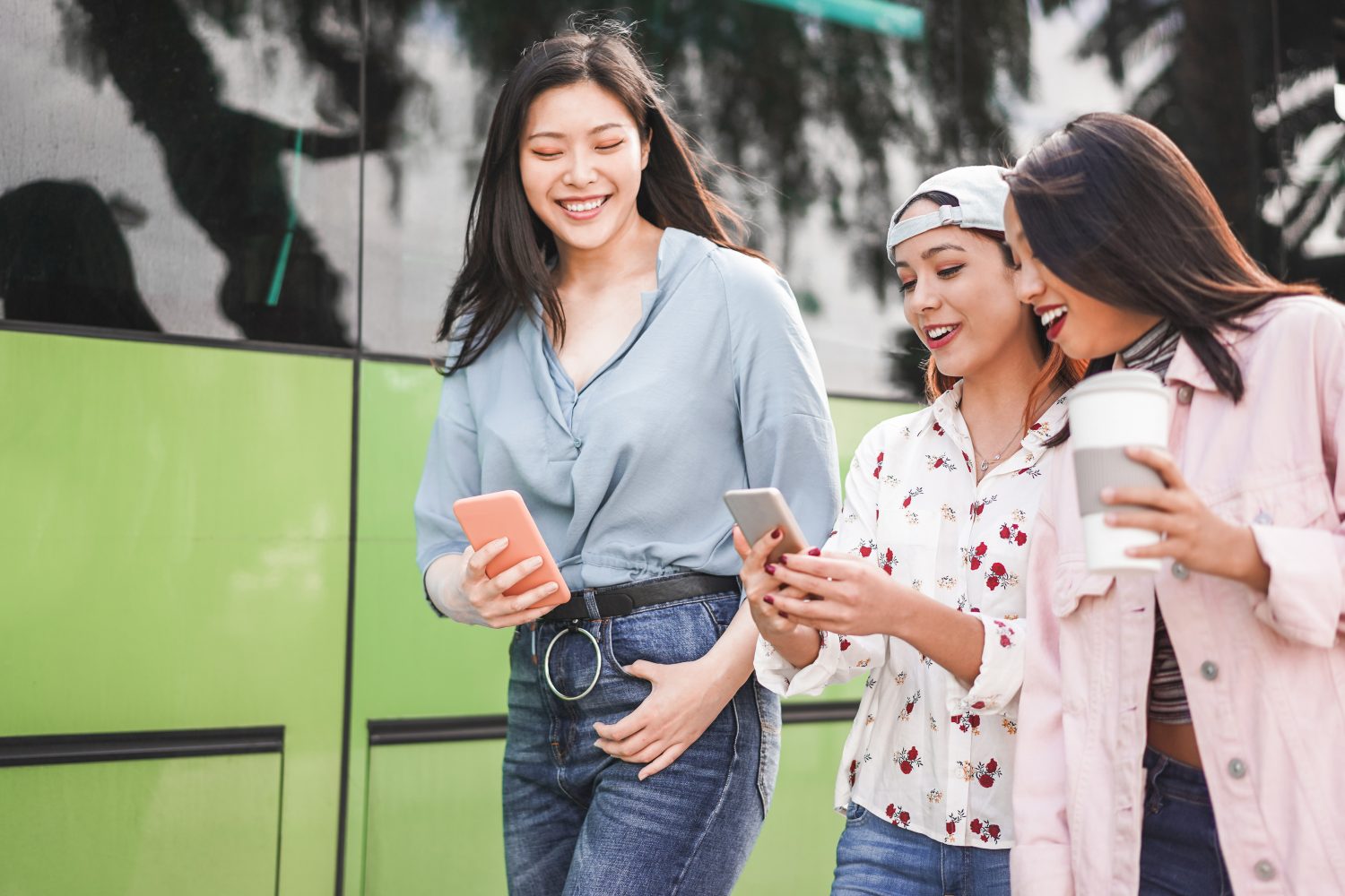 Felices amigos asiáticos que usan smartphones en la estación de autobuses / mantenerte delgado