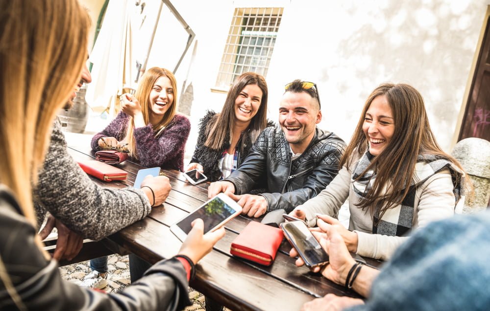 Grupo de amigos de la Generación del Milenio divirtiéndose usando el teléfono / perezosos / millennials