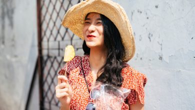 Joven mujer viajera tailandesa hermosa vestida de rojo y que disfruta comiendo pedazos de piña con un palo / piña