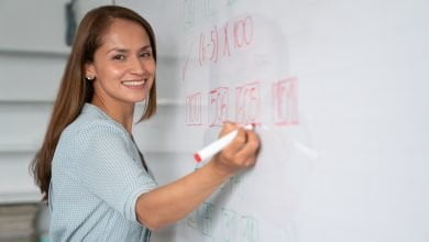 Educador feliz escribiendo instrucciones en tablero blanco / salario de docentes / vacantes