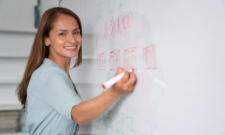 Educador feliz escribiendo instrucciones en tablero blanco / salario de docentes / vacantes