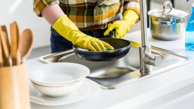 Imagen recortada de una mujer lavando una sartén en la cocina / olor a huevo