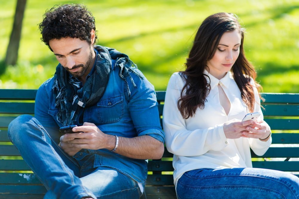 Pareja que no habla entre sí escribiendo en teléfonos móviles / solteros