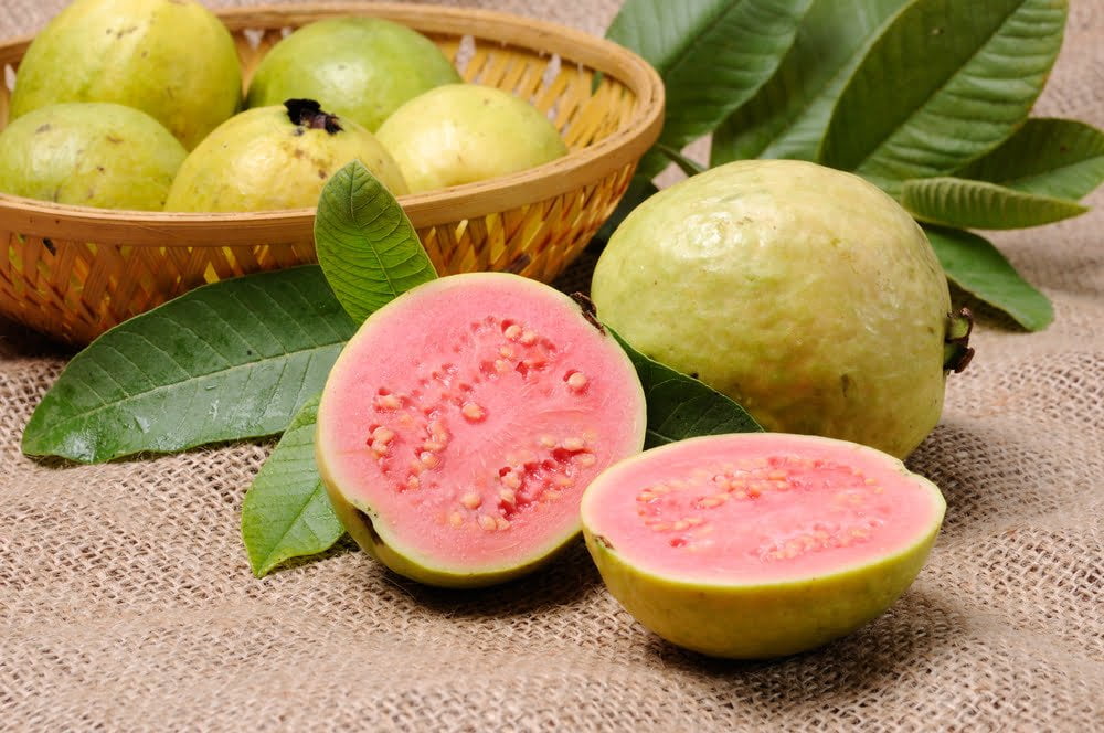 Una cesta llena de guayabas brasileñas sobre una superficie de madera / guayaba